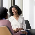 Mature counselor listens compassionately to unrecognizable female client