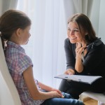 Woman elementary school teacher testing talking to girl