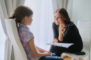 Woman elementary school teacher testing talking to girl
