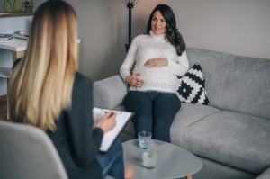 visibly pregnant woman speaks with a counselor