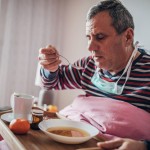 sick man uses eating soup in bed