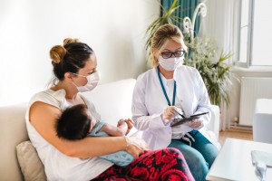 Female Pediatrician visiting newborn baby at home during quarantine