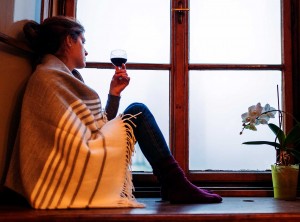 Woman Looking Out Window With Drink In Hand