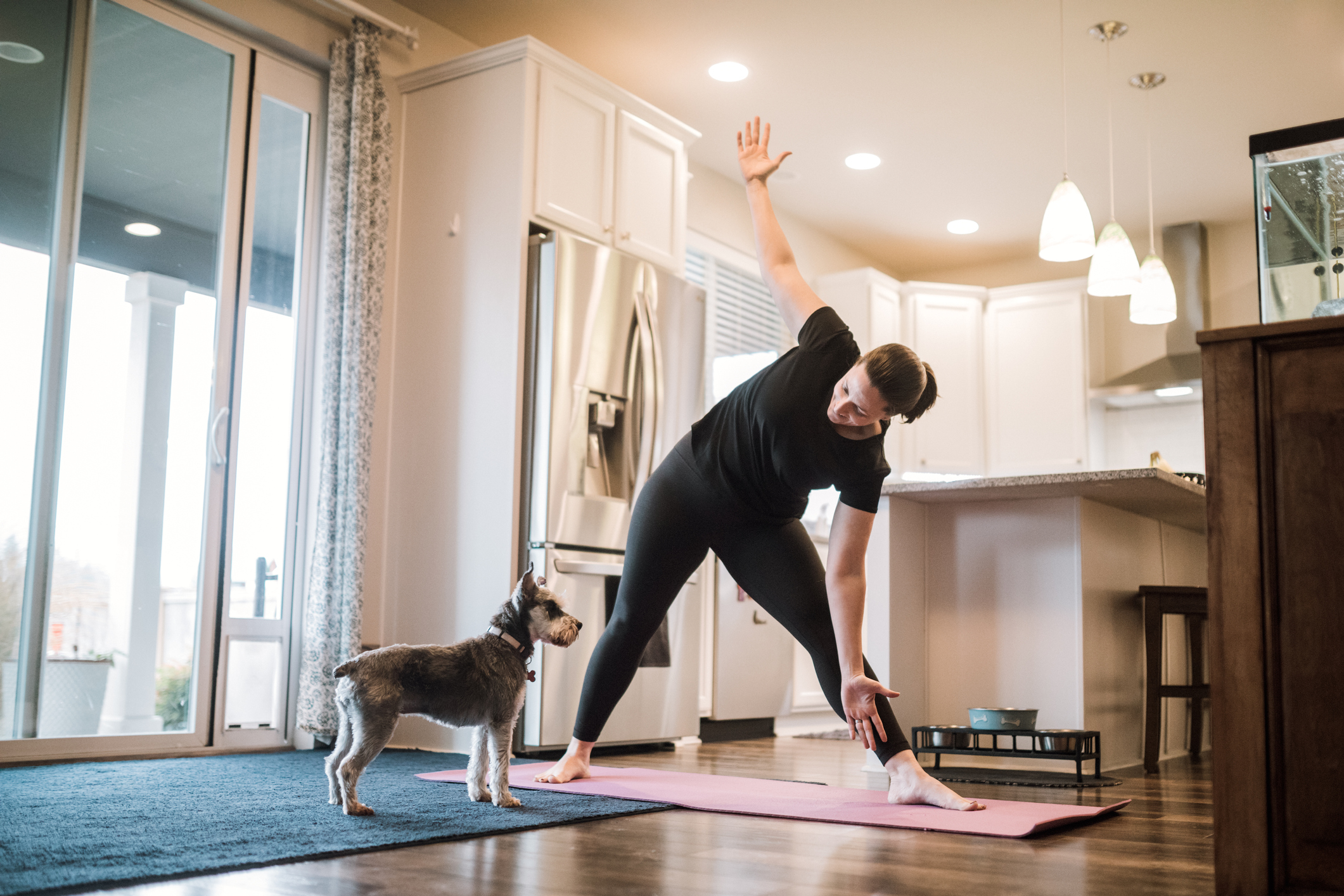 woman doing yoga at home with small dog nearby