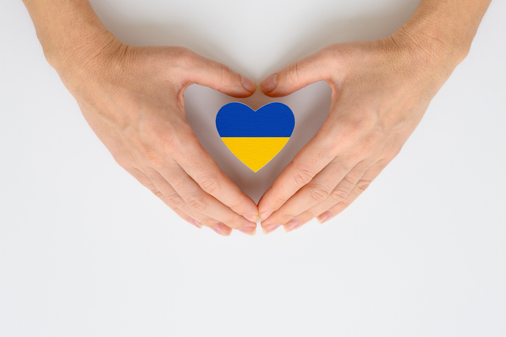 blue and yellow heart surrounded by hands