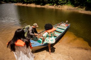 Tourist friends women boarding boat by river in forest