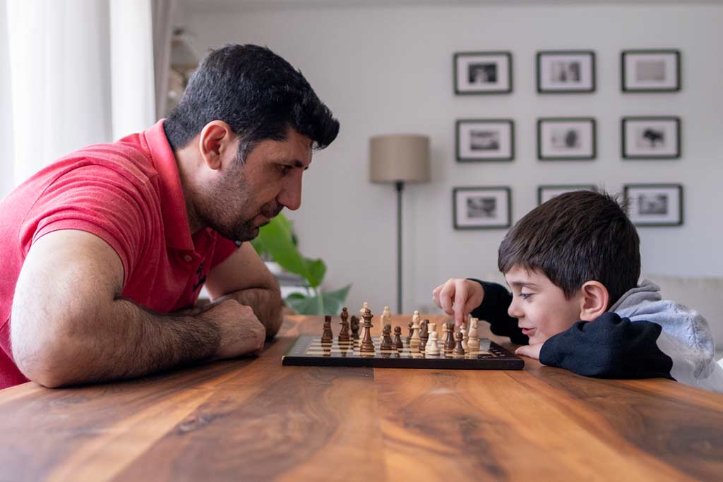 man and young boy playing chess at home