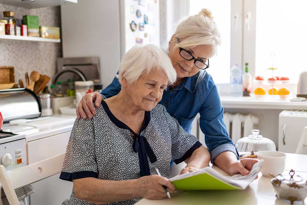 mature woman helping elderly mother with paperwork